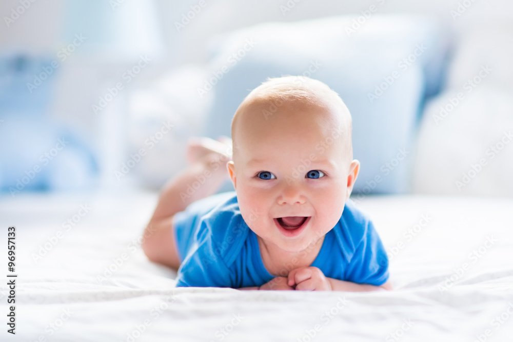 Baby boy lying in a bright white sunlit nursery, surrounded by newborn essentials from a baby registry
